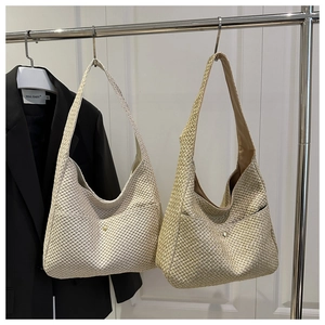 Detail of woven straw shoulder bag showing honeycomb texture and metal rivet detail