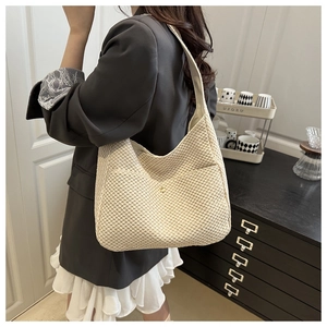 Dettaglio della borsa tote in paglia intrecciata beige con trama in maglia e tocco oro