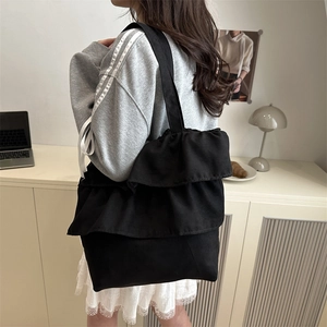 Black canvas tote bag with triple-layered ruffle trim and large capacity for daily use
