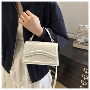 Détail du sac blanc gaufré avec rabat ondulé posé sur un meuble de rangement