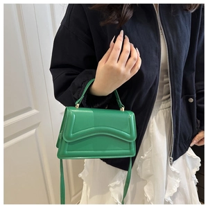 Détail du sac bandoulière vert vif montrant la texture gaufrée ondulée et les boucles dorées
