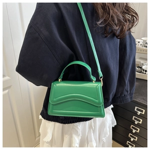 Dettaglio della borsa in pelle PU verde brillante con motivo a onde indossata dal modello