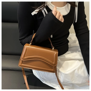 Détail du sac en cuir marron avec rabat à bords ondulés et boucles dorées chic