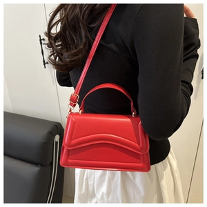 Dettaglio borsa in pelle goffrata rossa con cuciture a onde e hardware dorato