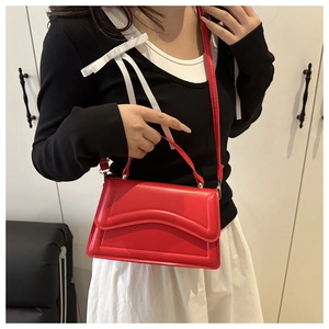 Dettaglio della borsa rossa in pelle PU con patta trapuntata a onde e tracolla regolabile