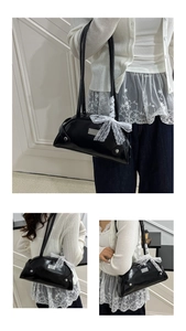 Detail of glossy patent leather shoulder bag with white lace bow and silver brand logo