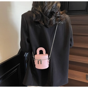 Vue arrière du mini sac cylindre rose porté avec un blazer noir dans un escalier