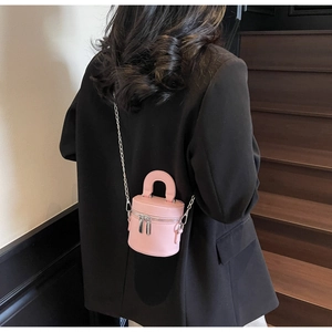 Rosa Mini-Zylindertasche mit Silberkette und Griff auf einem schwarzen Blazer getragen