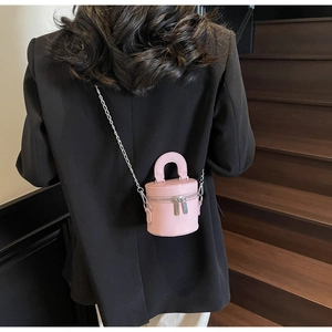Modellansicht der rosa Mini-Zylindertasche mit Silberkette auf schwarzem Blazer