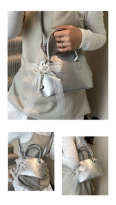 Detail of silver shell bag featuring a delicate lace pearl bow charm and leather texture