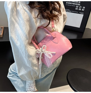 Detailaufnahme der rosa Bowlingtasche mit Perlenspitzen-Schleife an einem Modestil