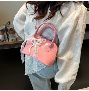Rosa Bowlingtasche mit Spitzenschleife und Perlenkette getragen von einem Model
