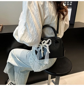 Detail der schwarzen Boston Bag mit weißer Spitzenschleife und Perlenanhänger