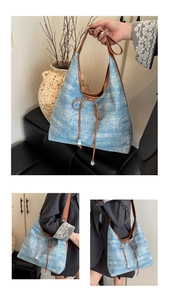 Detail of light blue denim tote bag with rhinestones, brown leather straps and bow