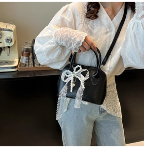 Detail der schwarzen Bowlingtasche mit großer Spitzenschleife, Perlenketten und Herzanhänger
