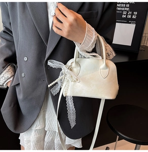 Detail der weißen glänzenden Bowling-Tasche mit Schleife aus Spitze und Perlen