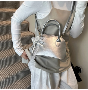 Detail der silbernen Metallic-Tasche mit Anhängern aus Spitze und Perlen Schleifen