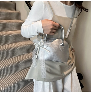 Detail der silbernen Bowlingtasche mit Perlenbogen, Spitzenelementen und Schultergurt