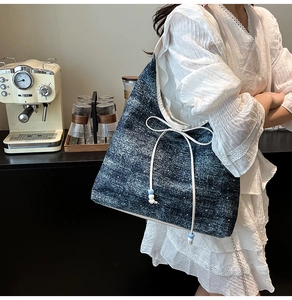 Detail of crescent shoulder bag featuring dark blue textured fabric and a white bow knot