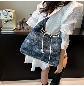 Close-up of washed denim shoulder bag featuring white polka dots and beaded rope detail