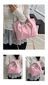 Close-up of pink bucket bag with white lace bow detail and adjustable shoulder strap