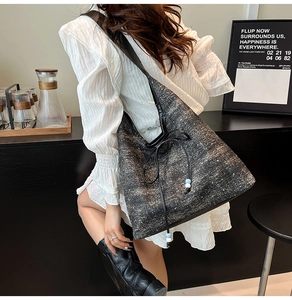 Detail of dark gray tweed tote bag with drawstring closure and blue bead accents