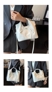 Detailed view of white leather handbag featuring a decorative lace bow and top handles