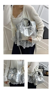 Detail of silver metallic handbag featuring delicate white lace bow and glossy finish