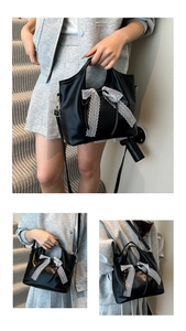Detail of black faux leather tote bag featuring two large white lace ribbon bows