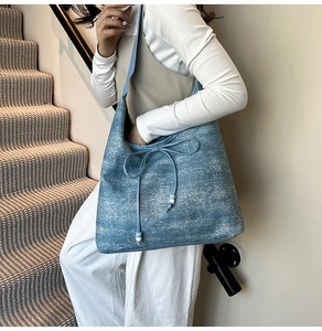 Detail of washed denim blue tote bag with drawstring tassels and white bead accents
