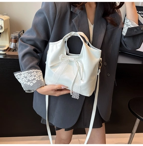 Dettaglio di una borsa tote bianca in PU opaco con elegante fiocco in pizzo e tracolla sottile