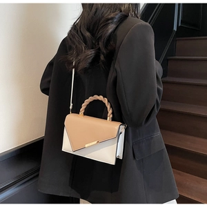 Detail of color-block crossbody bag with woven handle and asymmetrical beige flap