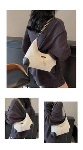 Détail d'un sac hobo tissé beige avec pendentif cerf doré et bandoulière chaîne