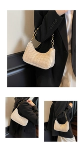 Detail der handgewebten cremefarbenen Baguette-Tasche mit goldener Metallkette