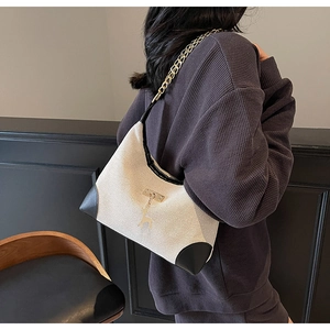 Detail of canvas and black leather shoulder bag with golden chain and deer pendant