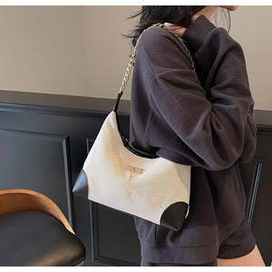 Détail du sac hobo en toile avec garniture cuir, chaîne dorée et pendentif cerf porté
