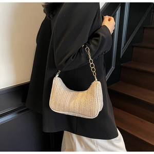 Detail der gewebten Stroh-Schultertasche mit eleganter Goldkette und Halbmondform