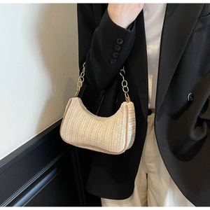 Detaillierte Textur der gewebten Stroh-Hobo-Tasche mit goldener Kette und brauner Paspel