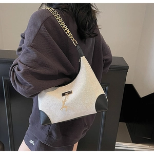 Détail du sac bandoulière en toile avec empiècements cuir et chaîne dorée chic