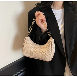 Detail of woven linen straw texture with bold gold chain strap on shoulder bag