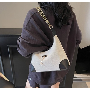 Détail du sac bandoulière en toile avec chaîne dorée et pendentif décoratif en métal