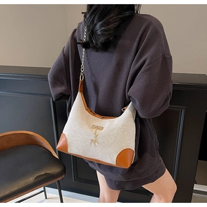Détail du sac cabas en toile beige avec garniture en cuir marron et pendentif cerf doré