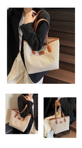 Close-up of off-white canvas tote bag with brown leather handles and textured fabric