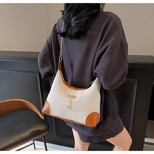 Vue détaillée d'un sac hobo en toile et cuir porté par un mannequin de dos en intérieur