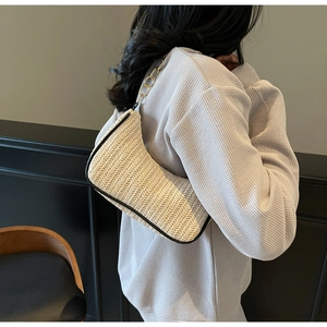 Detailed close-up of woven linen shoulder bag with black leather trim and gold chain strap