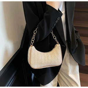 Detail of woven straw shoulder bag with elegant gold chain strap for summer style