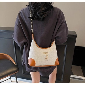 Vue arrière d'un mannequin portant un sac hobo en toile crème et finitions en cuir brun