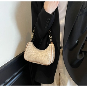 Detailierte Textur der gewebten Stroh-Hobo-Tasche mit Goldkette an professionellem Model
