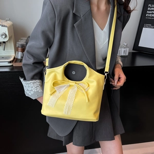 Borsa a secchiello gialla con fiocco in pizzo indossata da modella in abito grigio