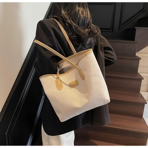 Detail of canvas tote bag showing cream fabric with brown leather straps on model shoulder